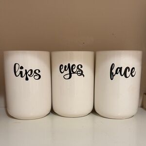 White ceramic canister set w/ text:lips,eyes,face. Perfect to make up counter